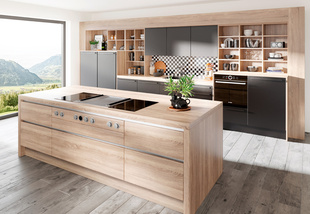DAN-Küche mit zentraler Kücheninsel, offenen Stellflächen, teilweise Glasfronten in Beige und Holzoptik